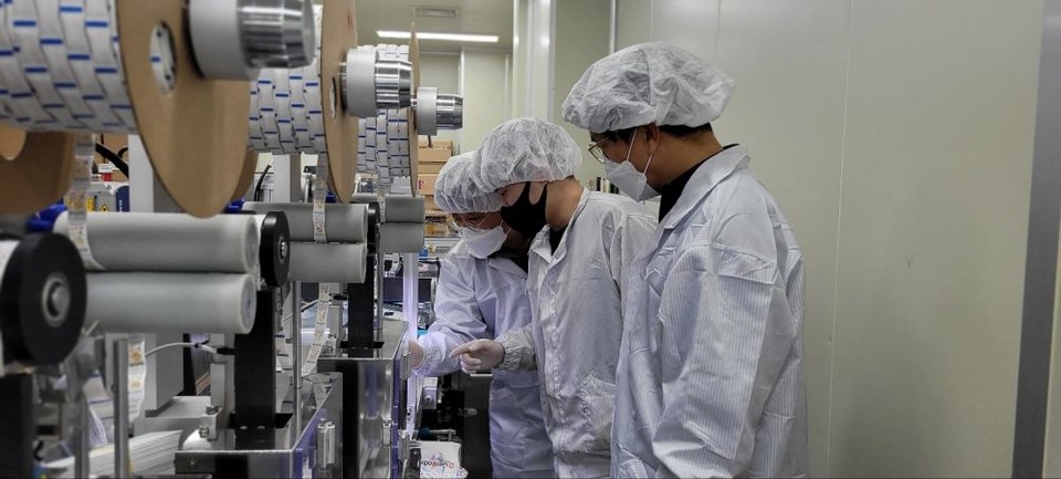 충남 천안에 위치한 자가진단키트 생산업체 ‘젠바디’에서 삼성전자 스마트공장 전문가와 젠바디 직원(가운데)이 자가진단키트 조립 라인을 점검하고 있다. [사진=삼성전자]