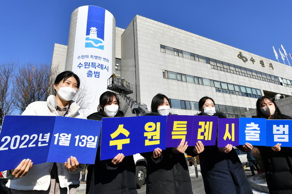 지난해 1월 특례시 출범을 앞두고 수원시청에 대형 현수막이 게시된 가운데 수원시 직원들이 특례시 출범을 축하하는 카드를 들고 있다.[사진=수원특례시]