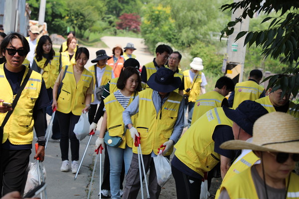 7개 공공기관 임직원과 자원봉사자들이 황구지천 산책로에 버려진 쓰레기를 줍고 있다.[사진=수원특례시]