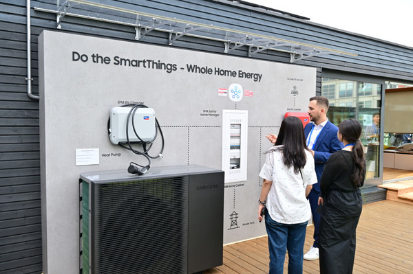 삼성전자 직원이 넷 제로 홈(Net Zero Home)’ 솔루션으로 꾸며진 타이니 하우스 외관에 소개된 SMA와 ABB의 에너지 생산/저장 시스템을 소개하고 있다. [사진=삼성전자]