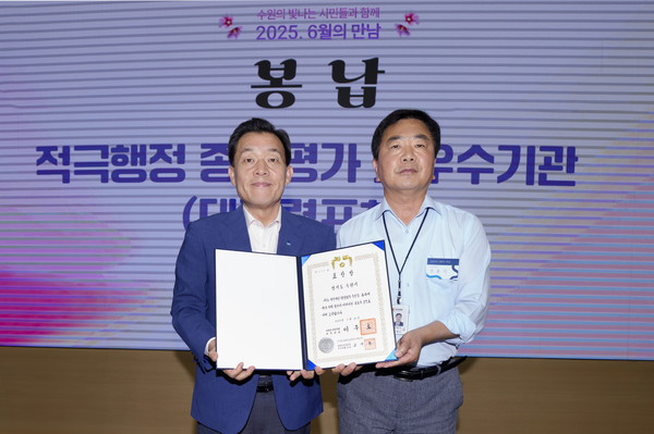 전용기 수원시 법무담당관이 9일 시청 중회의실에서 열린 ‘6월의 만남’ 행사 중에 이재준 수원시장(왼쪽)에게 대통령 표창을 봉납하고 있다.