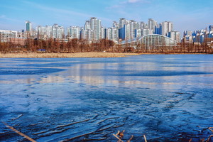 얼어붙은 일월저수지 수면 위로 아파트 등 도시의 풍경이 반사되고 있다.[사진=수원특례시]